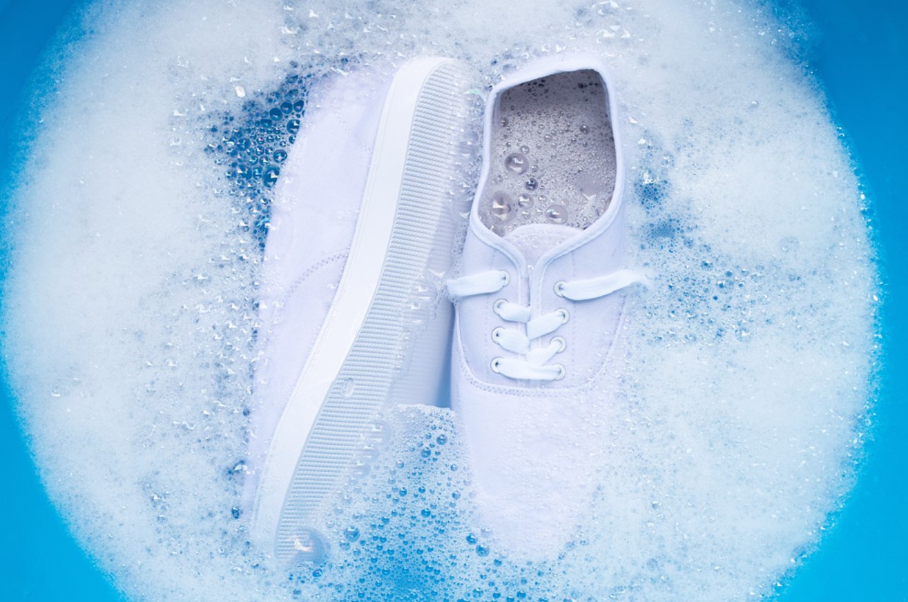 White sneakers being deep cleaned in soapy water